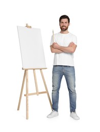 Photo of Happy man with brush near easel with canvas on white background. Creative hobby
