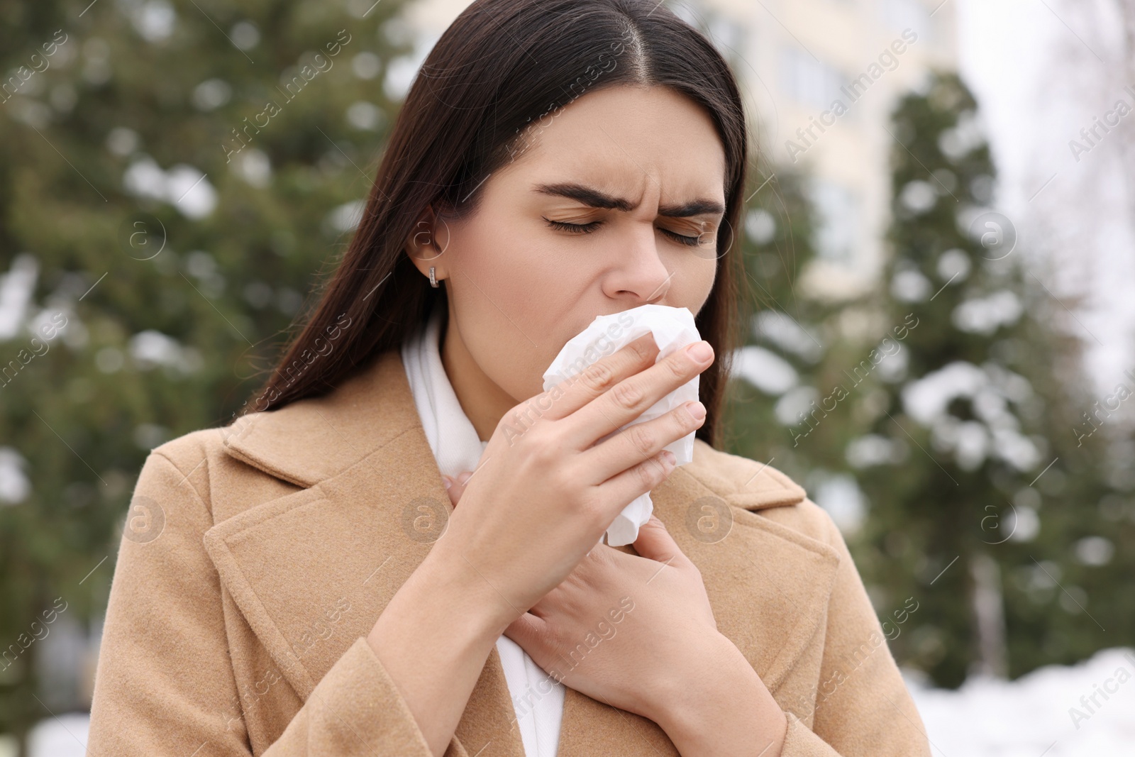 Photo of Woman in coat coughing outdoors. Cold symptoms