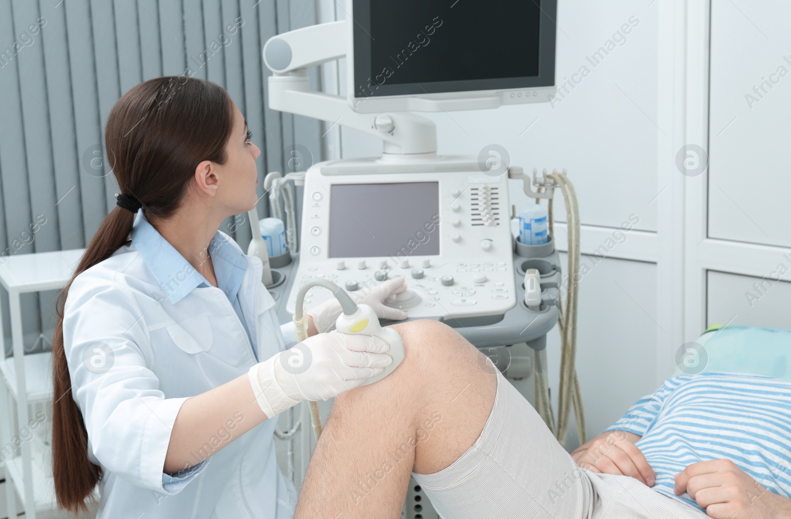 Photo of Doctor conducting ultrasound examination of patient's knee in clinic