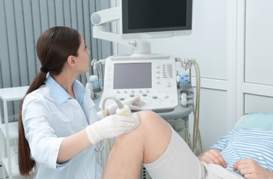 Doctor conducting ultrasound examination of patient's knee in clinic