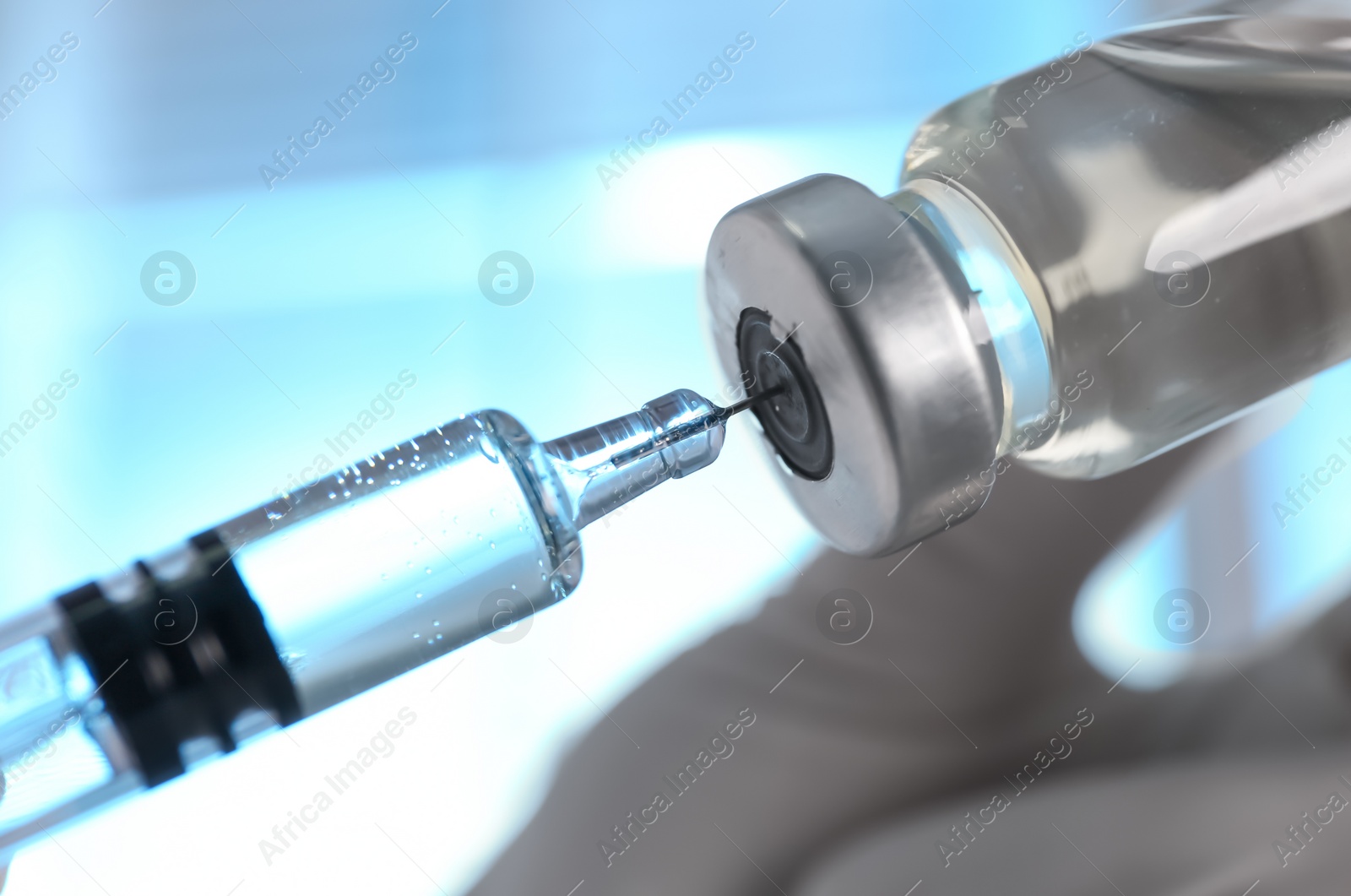 Photo of Doctor filling syringe with vaccine from vial on blurred background, closeup