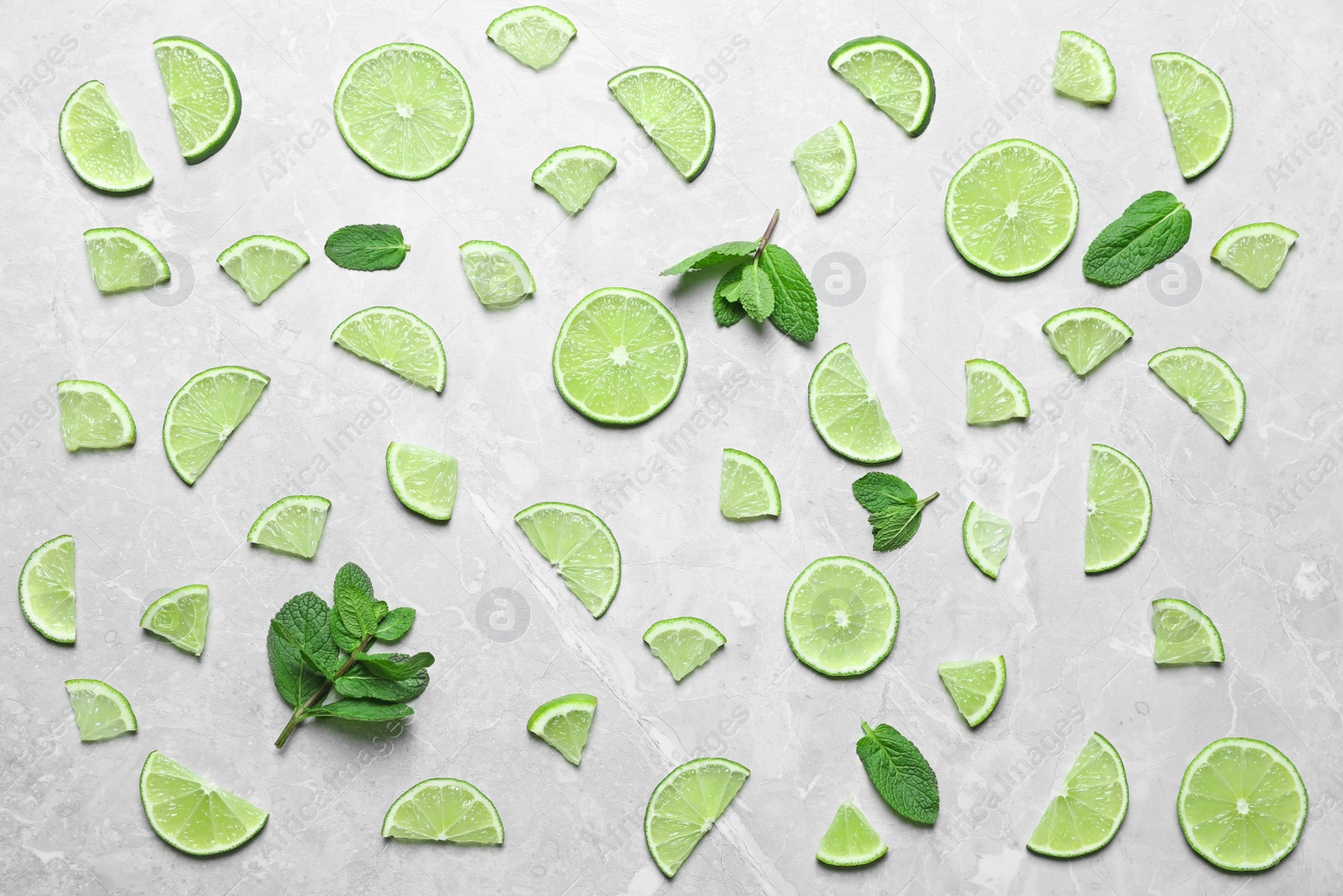 Photo of Slices of fresh juicy lime on marble table, flat lay