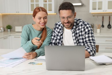 Photo of Couple using laptop for paying taxes online at home