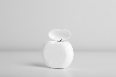 Container with dental floss on white background