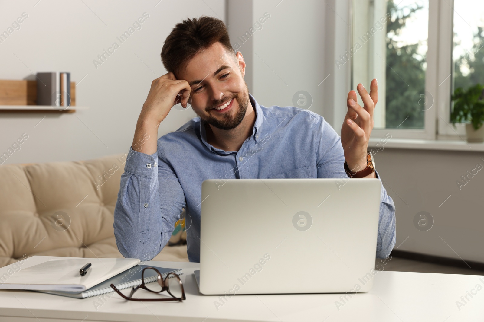 Photo of Handsome man working with laptop at table indoors