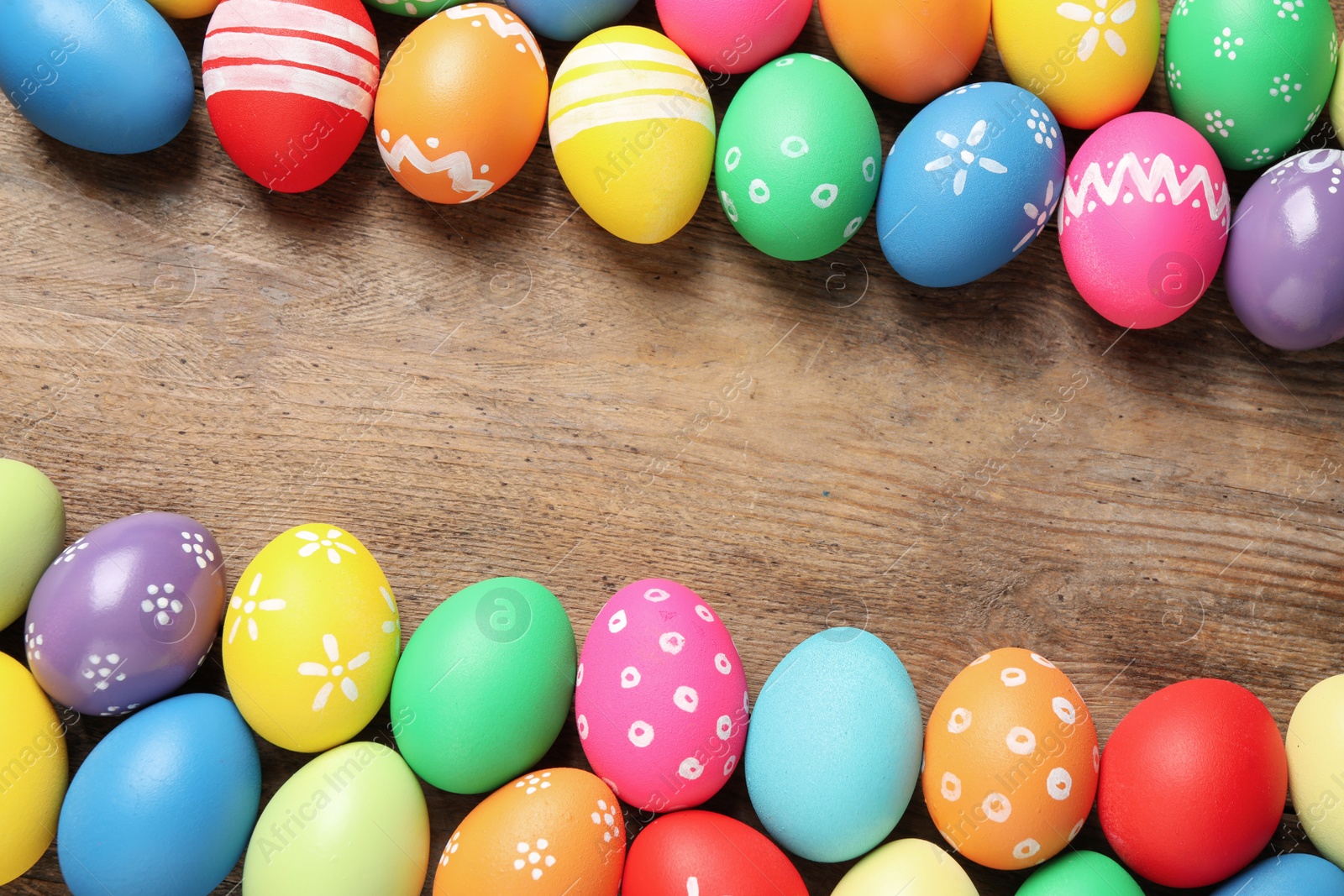 Photo of Frame made with colorful Easter eggs on wooden background. Space for text