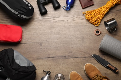 Photo of Flat lay composition with different camping equipment on wooden background, space for text