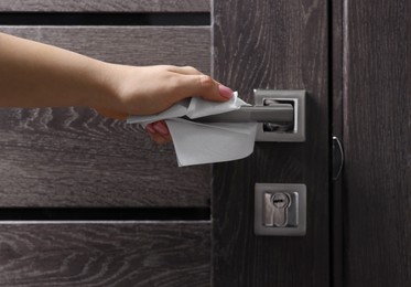 Photo of Woman wiping door handle with paper towel, closeup