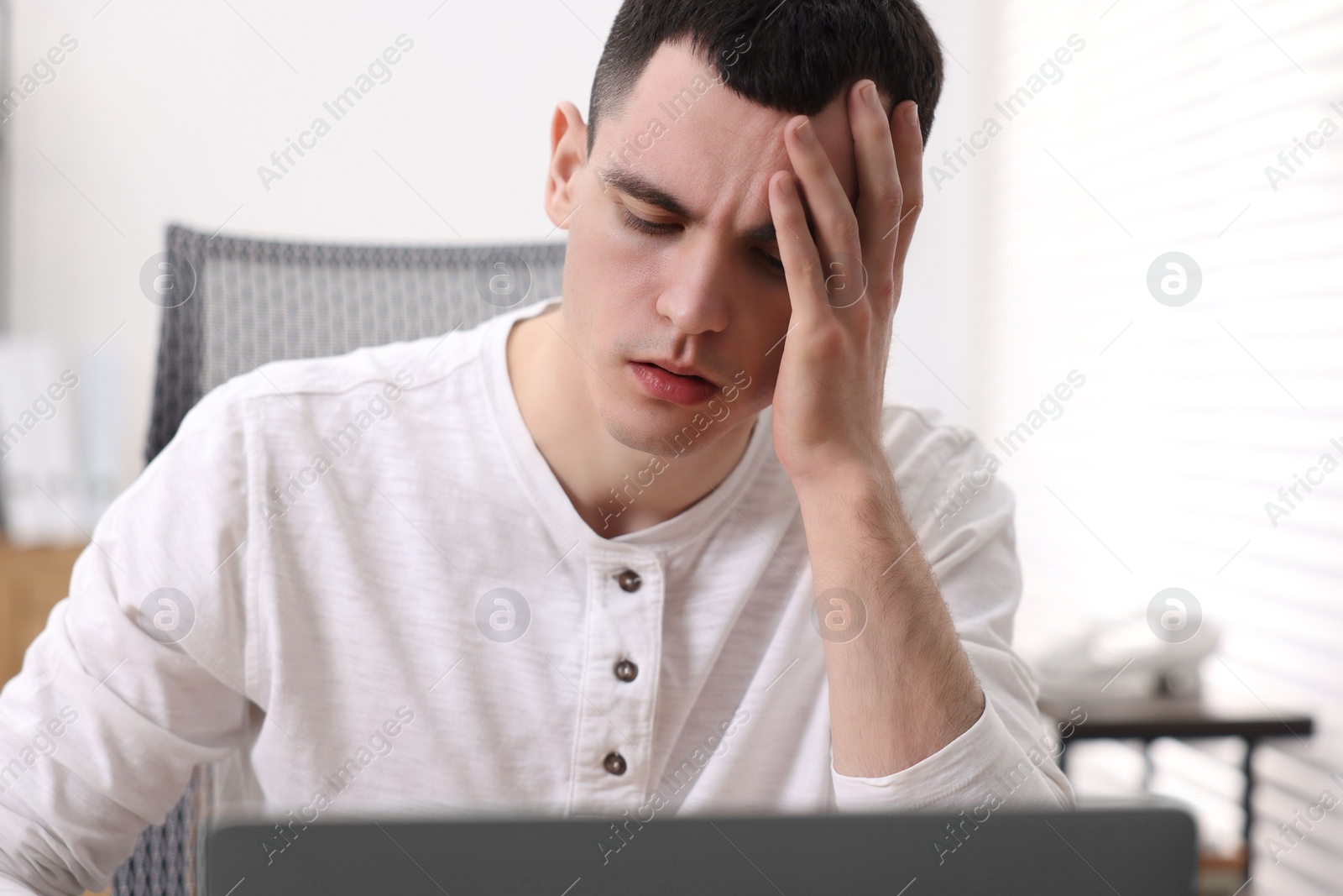 Photo of Young man suffering from headache in office