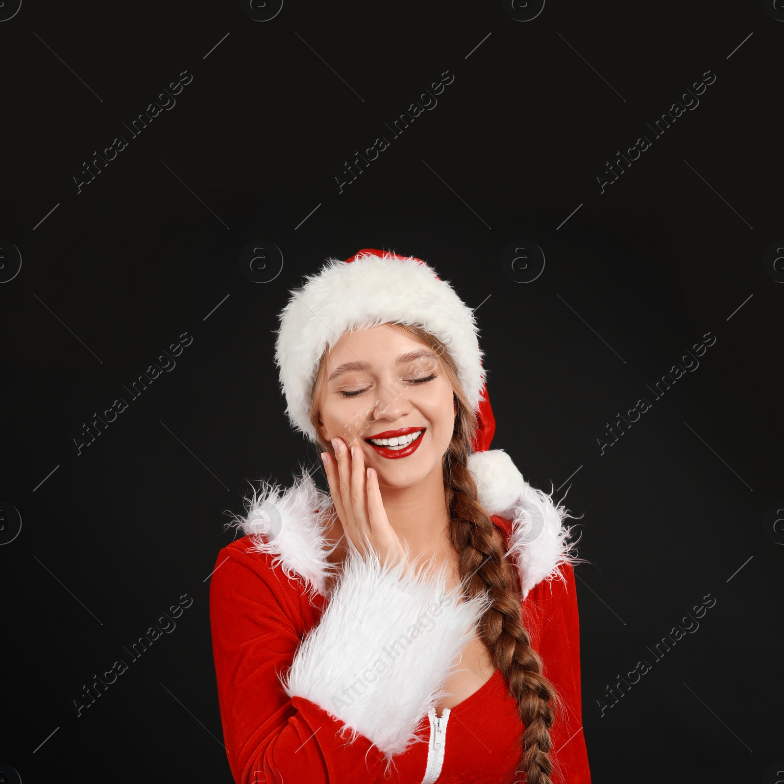 Photo of Beautiful Santa girl on black background. Christmas eve