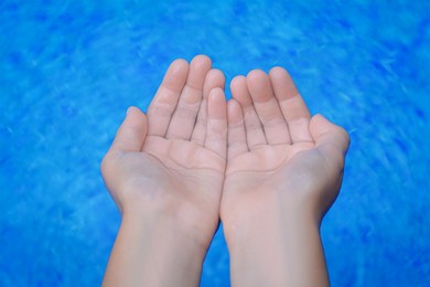 Photo of Girl holding water in hands above pool, closeup