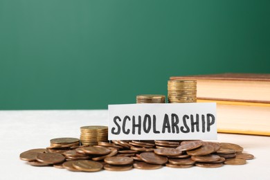 Photo of Paper with word Scholarship, coins and books on white table