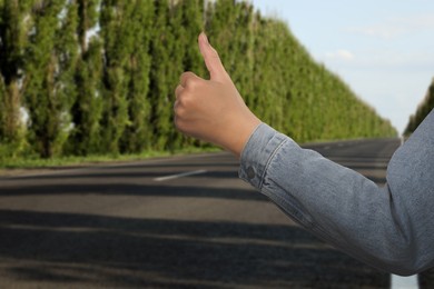 Woman catching car on road, closeup. Hitchhiking trip