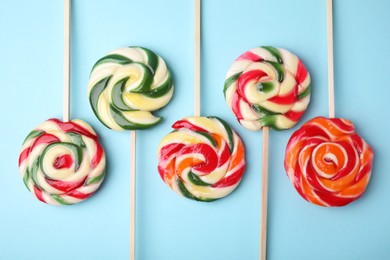 Photo of Many colorful lollipops on light blue background, flat lay