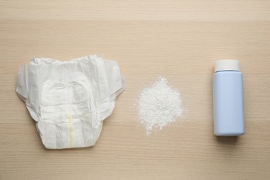 Photo of Dusting powder and diaper on wooden background, flat lay. Baby care products