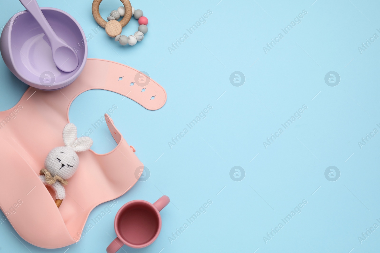 Photo of Set of plastic dishware and baby accessories on light blue background, flat lay. Space for text