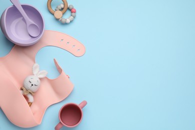 Photo of Set of plastic dishware and baby accessories on light blue background, flat lay. Space for text