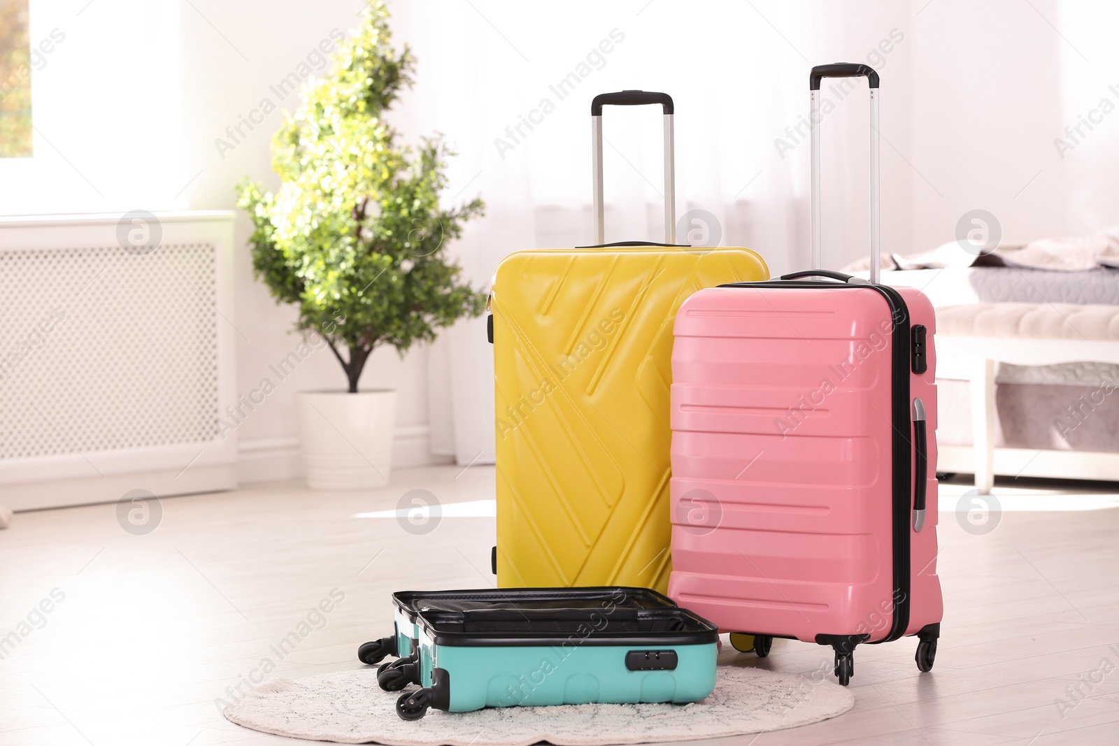 Photo of Colorful suitcases packed for journey in bedroom. Space for text