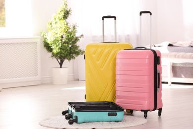 Colorful suitcases packed for journey in bedroom. Space for text