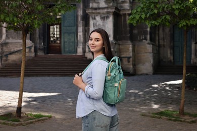 Photo of Travel blogger with backpack recording video on city street