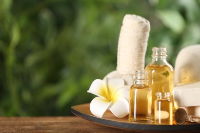 Beautiful spa composition with aroma oil and flower on wooden table, closeup. Space for text