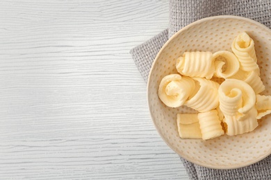 Plate with butter curls on table, top view