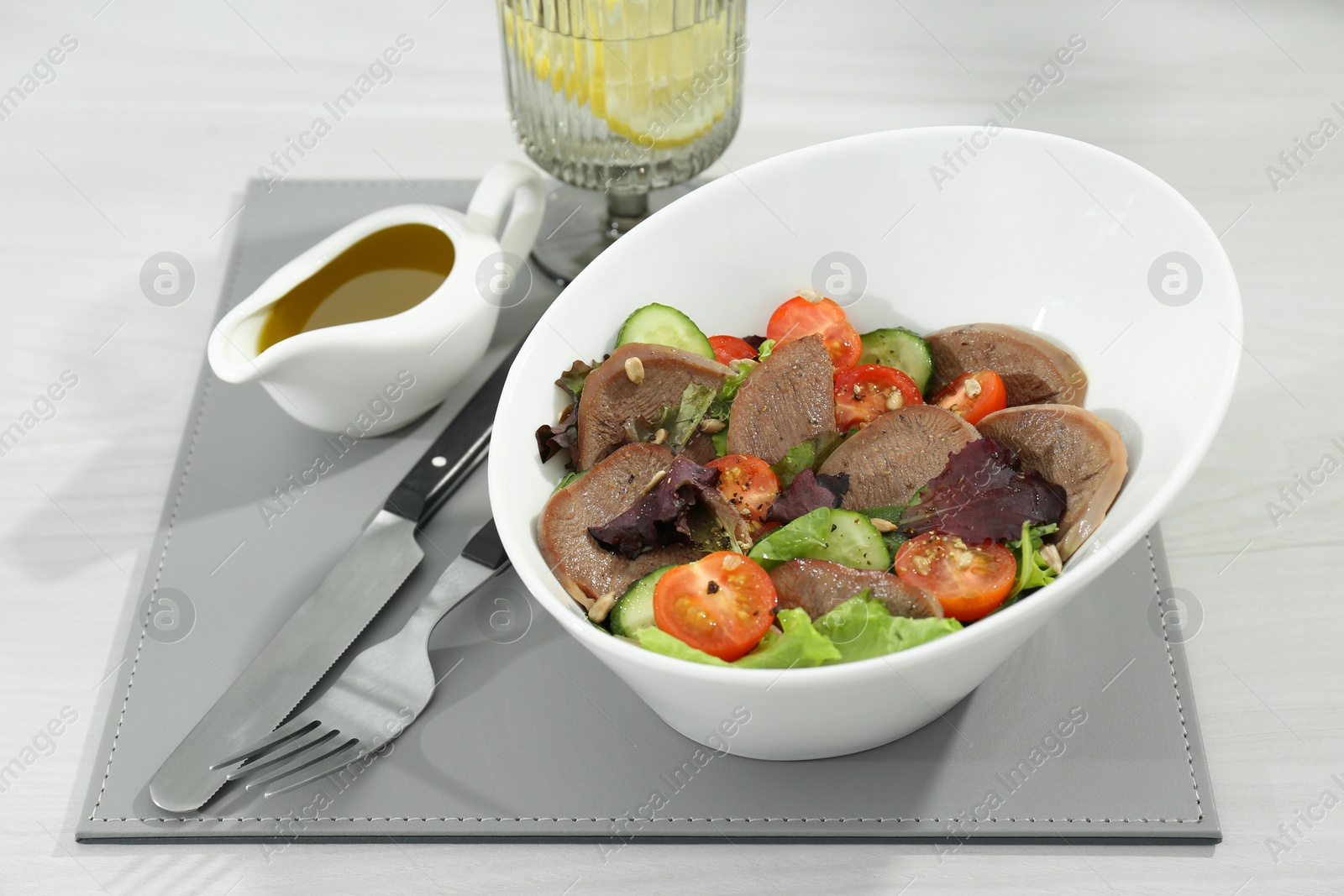 Photo of Delicious salad with beef tongue and vegetables served on white wooden table