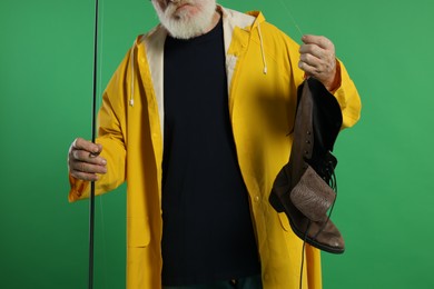 Photo of Fisherman with rod and old boot on green background, closeup