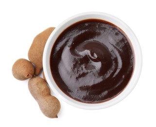 Photo of Bowl of tamarind sauce and fresh pods isolated on white, top view