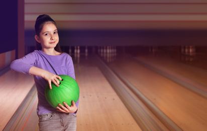 Photo of Little girl with ball in bowling club. Space for text