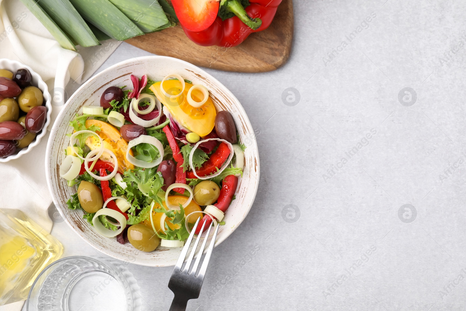 Photo of Bowl of tasty salad with leek and olives served on light table, flat lay. Space for text