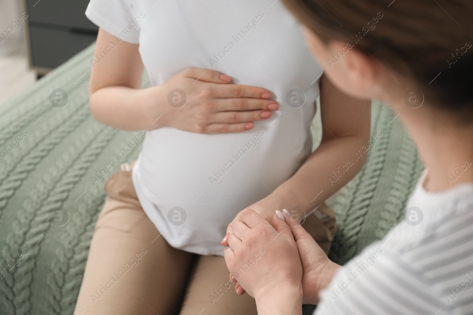 Photo of Doula taking care of pregnant woman indoors, closeup. Preparation for child birth