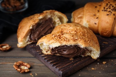 Tasty croissant with chocolate and sesame seeds on wooden table