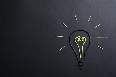 Photo of Light bulb made of plasticine on black background, top view. Space for text