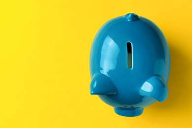 Photo of Ceramic piggy bank on yellow background, top view. Space for text