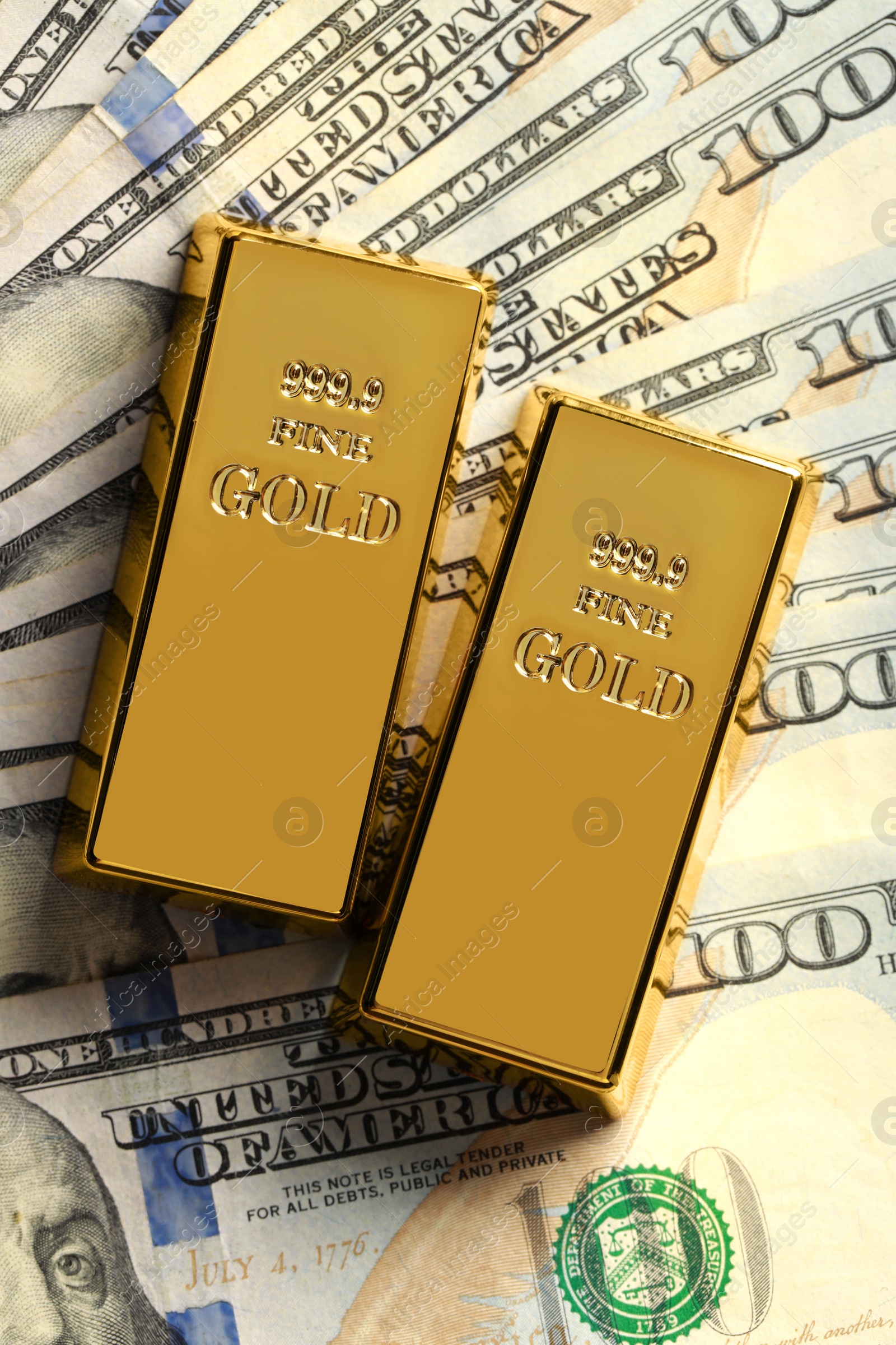 Photo of Shiny gold bars on dollar banknotes, flat lay