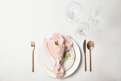 Festive table setting with plates, glasses, cutlery and napkin on light background, flat lay