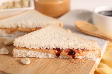 Photo of Sandwich with tasty nut butter and jam on wooden board, closeup