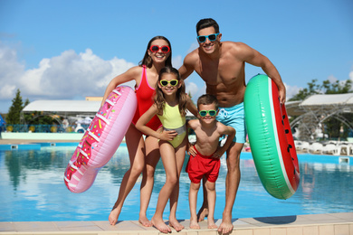 Photo of Happy family with inflatable rings near swimming pool.  Summer vacation