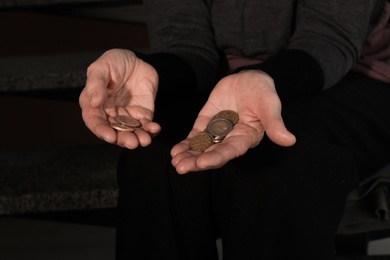 Poor mature woman with coins on stairs, closeup