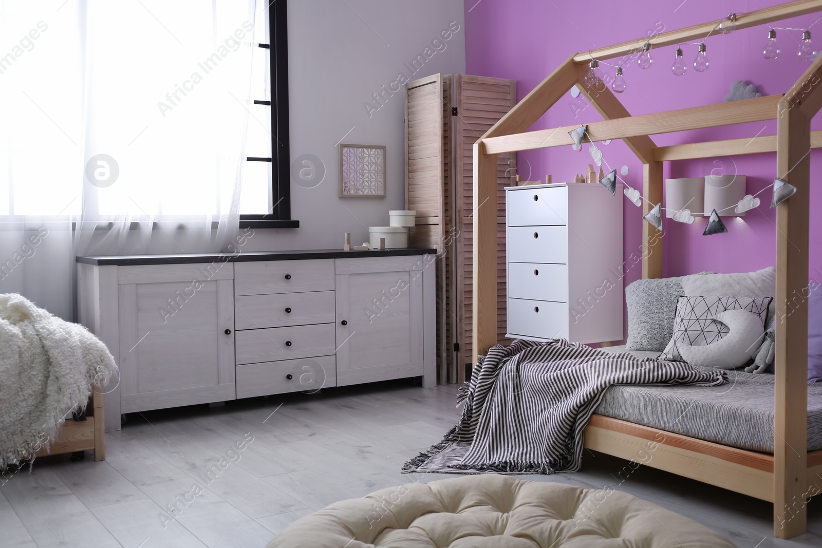 Photo of Child's room interior with comfortable bed and garland