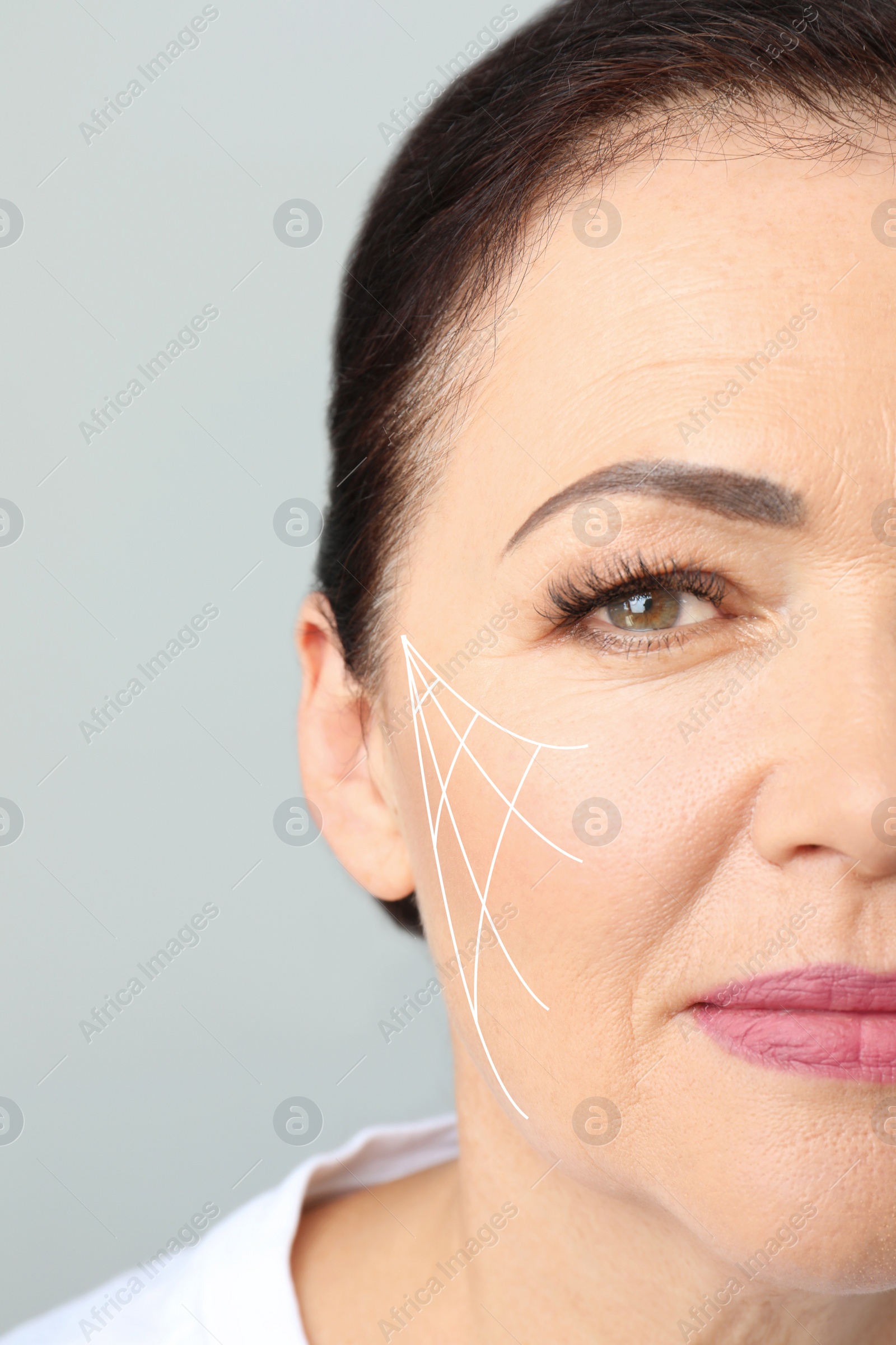 Image of Beautiful mature woman after facelift cosmetic surgery procedure on grey background, closeup