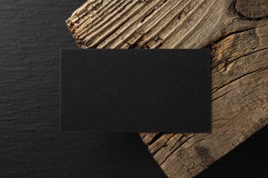 Photo of Empty business card and piece of wood on black background, top view. Mockup for design