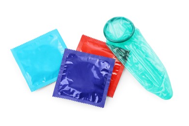 Photo of Unrolled condom and packages on white background, top view. Safe sex