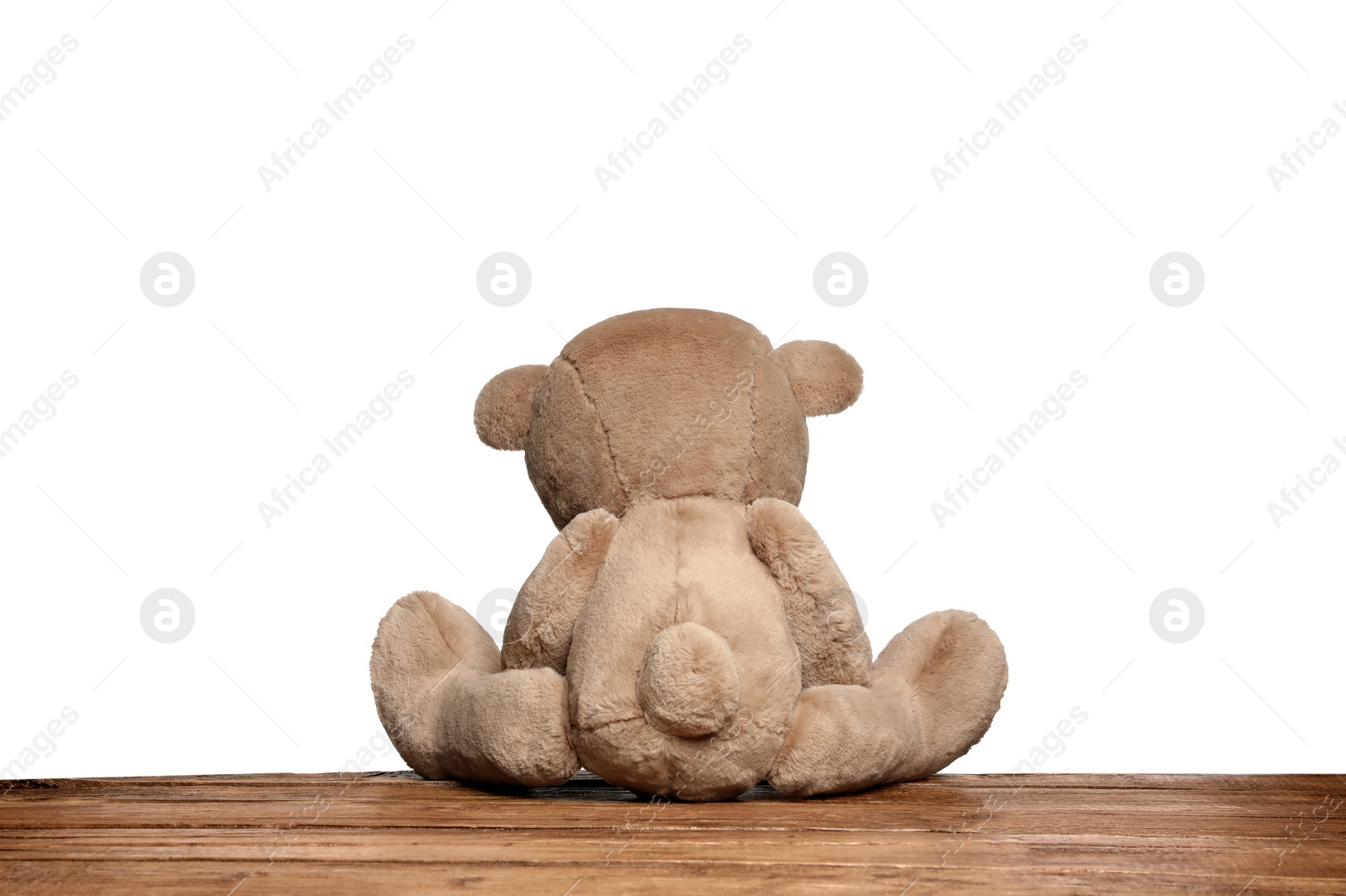 Photo of Cute teddy bear on wooden table against white background, back view