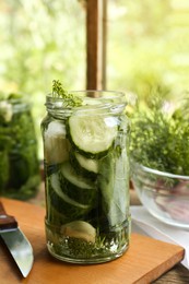 Glass jar with cucumber slices, dill and brine on table indoors. Pickling recipe