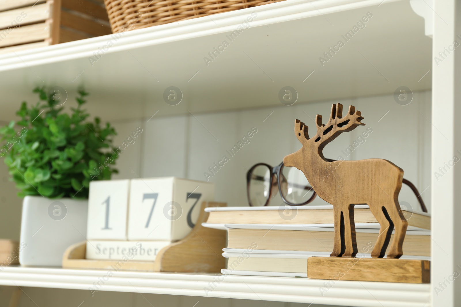 Photo of White shelving unit with wooden deer figure, books and calendar