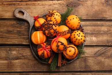 Photo of Pomander balls made of fresh tangerines and cloves on wooden table, top view