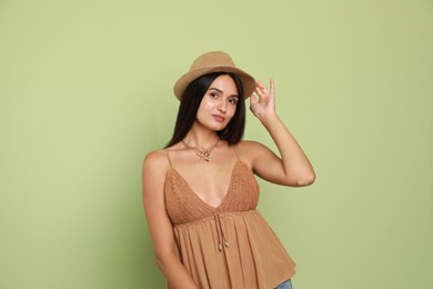 Photo of Beautiful young woman with straw hat on light green background