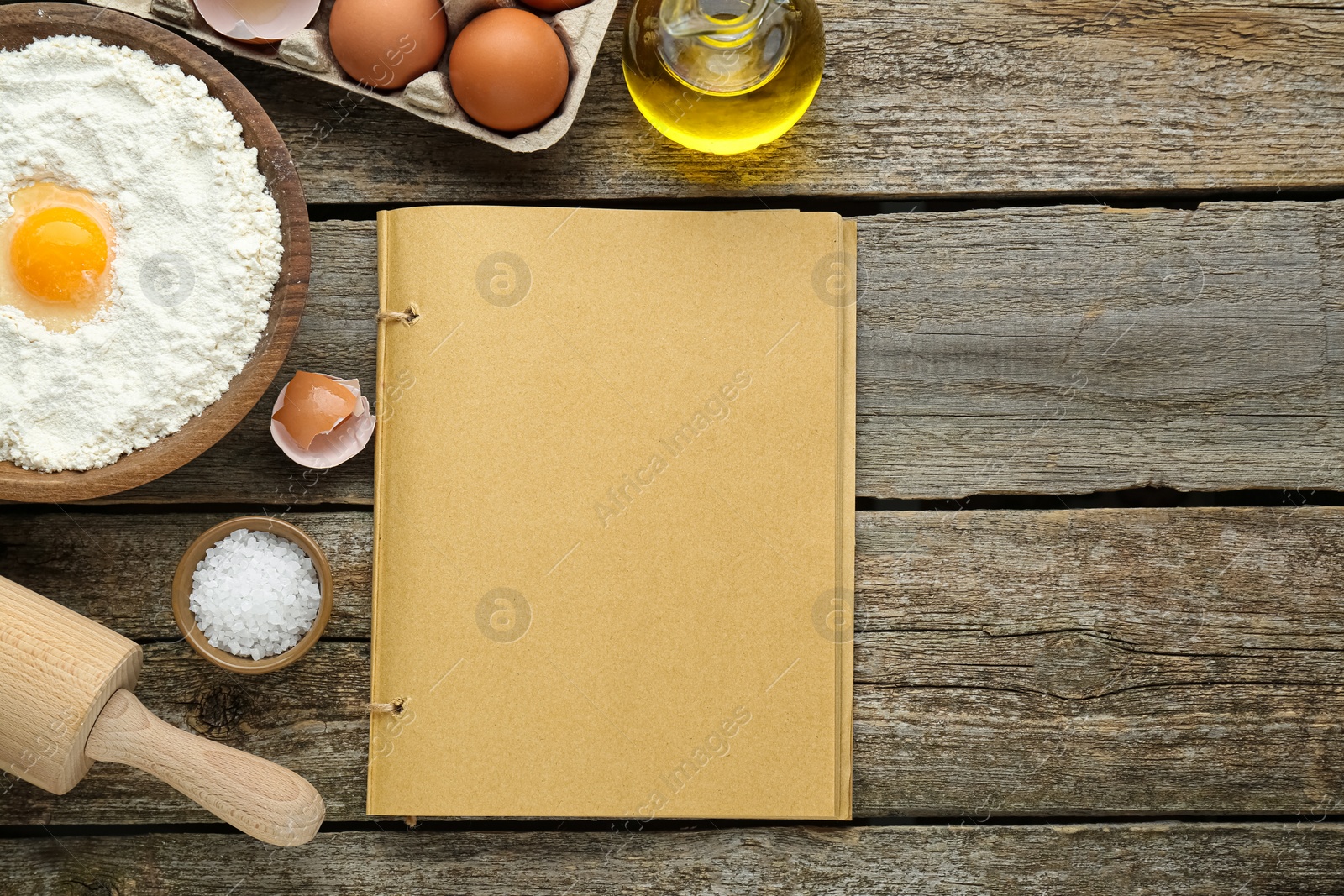 Photo of Blank recipe book and different ingredients on wooden table, flat lay. Space for text